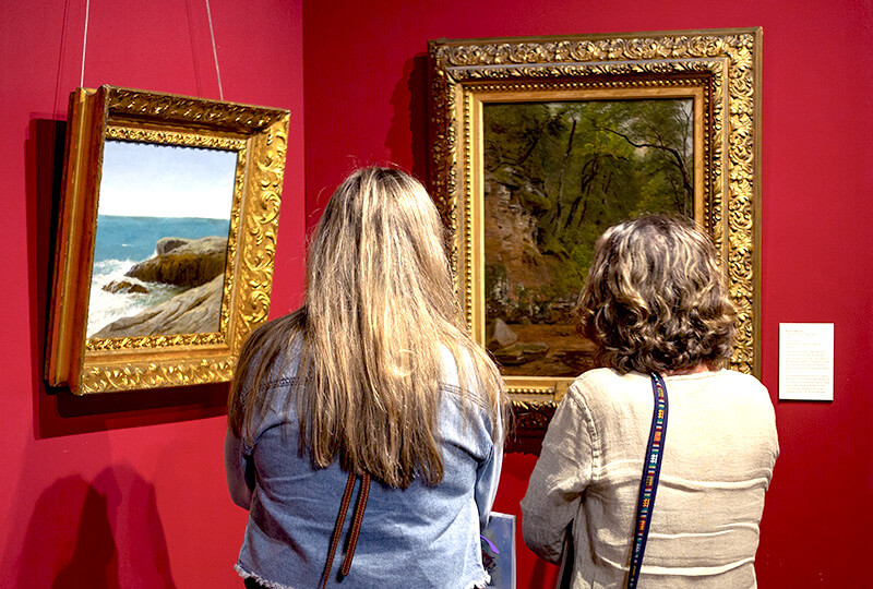 Two women viewing paintings in the T.W. Wood Gallery
