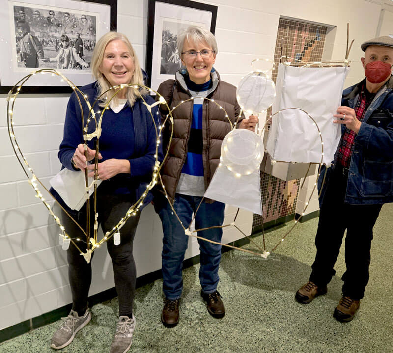 Three adults showing the lighted lanterns they created