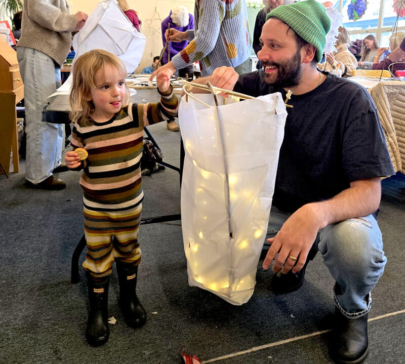 A father and daughter holding their lighted lantern they created