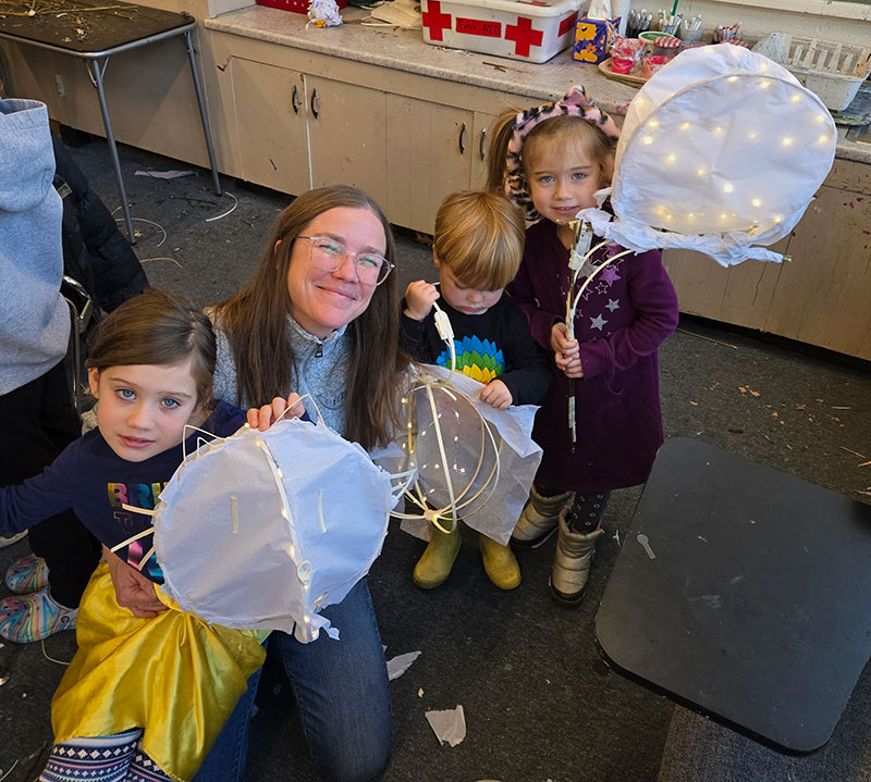 A mom with her three kids and the lighted lanterns they made